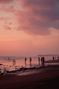 Silhouette people on beach against sky during sunset