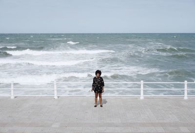 Woman standing against sea in sunny day