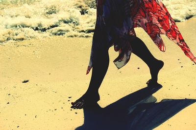 Low section of woman walking at beach