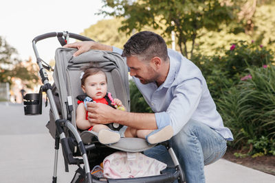 Caucasian proud father walking with baby daughter in stroller. family dad and daughter together 