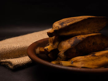 Stack of boiled bananas on a round pottery plate. shoot on a black background