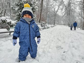 Smiling kid walking and playing in the snow at the park