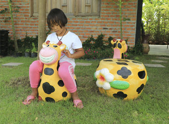 Child girl enjoy sitting on giraffe statue.