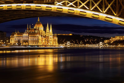 Illuminated hungarian parliament building by danube river at night