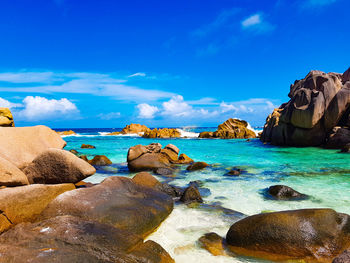 Rocks on beach against blue sky