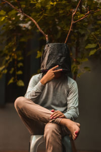 Midsection of man sitting against tree