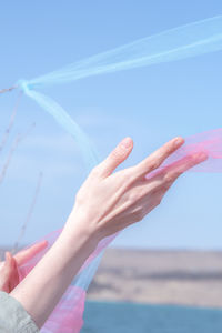 Low section of woman with arms raised at beach