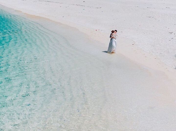 WOMAN STANDING ON SANDY BEACH