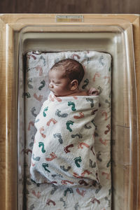 Overhead view of newborn infant boy swaddled in hospital bassinet