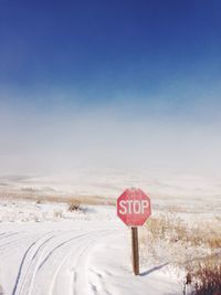 Information sign on snow covered landscape against clear sky