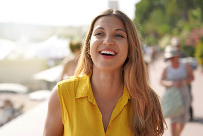 Close-up of laughing woman with yellow shirt walking on cannes promenade, france