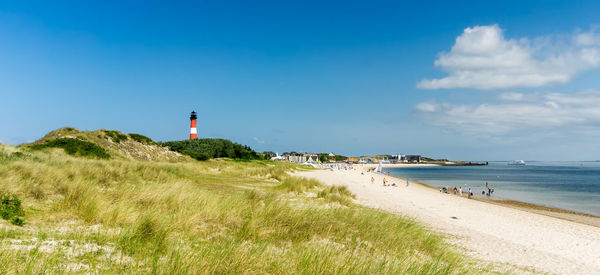 Lighthouse on beach against blue sky