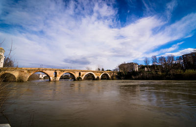 Arch bridge over river against sky