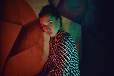 Portrait of beautiful woman standing against abstract wall