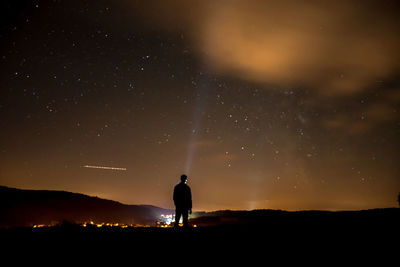 Rear view of man standing on mountain at night