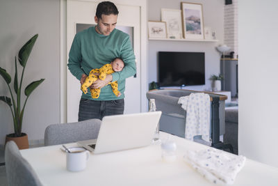 Full length of man using mobile phone at home