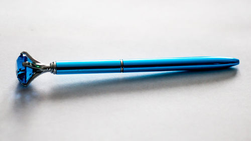 Close-up of blue pen with diamond against gray background