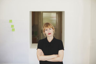 Portrait of woman standing against wall