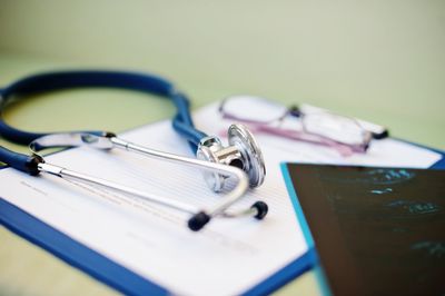 High angle view of stethoscope with medical x-ray and medical reports on wooden table