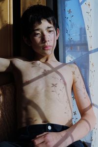 Portrait shirtless boy sitting at home