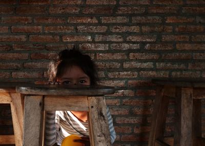 Portrait of girl against brick wall