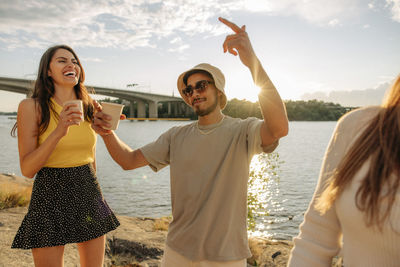 Young man holding drink and dancing with friends during picnic