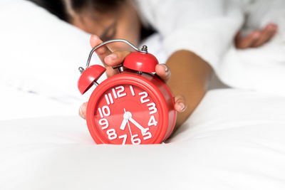 Close-up of alarm clock with woman sleeping in background