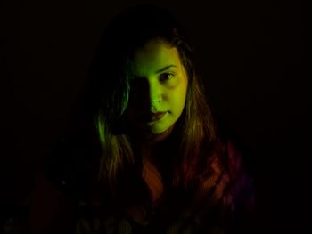 Portrait of young woman against black background