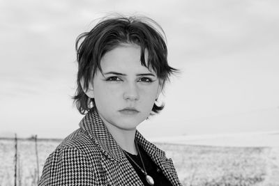 Portrait of beautiful young woman by sea against sky