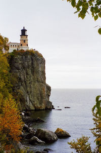 Lighthouse by sea against sky