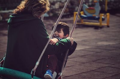 Grandmother and grandson enjoying swing at playground