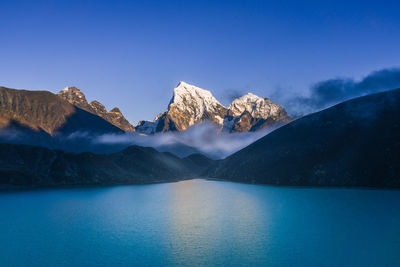 Scenic view of lake and mountains against clear blue sky