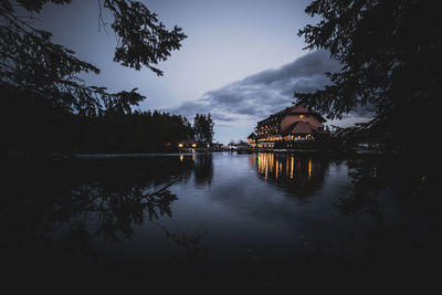 Scenic view of lake by buildings against sky at dusk