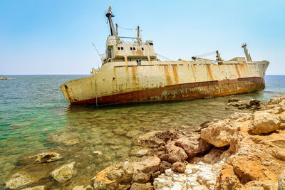 Abandoned ship in sea against clear sky