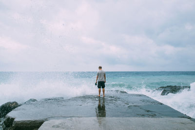 Man standing by edge of stone pier