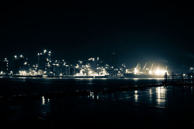 Illuminated harbor by sea against sky at night