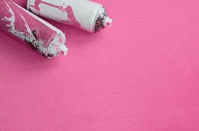 High angle view of spray bottles on pink background