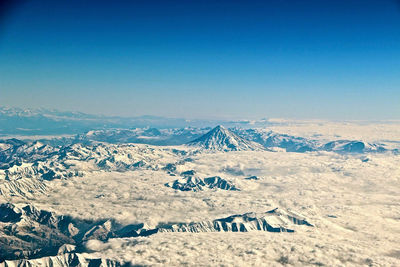 Aerial view of snowcapped mountains against clear blue sky