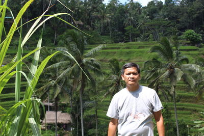 Portrait of young man standing against trees