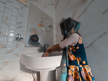 Rear view of woman standing in bathroom