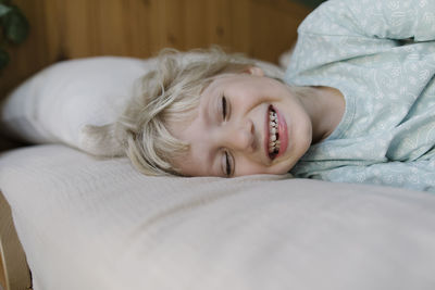 Happy girl with eyes closed lying on bed at home