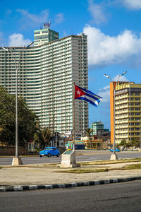 Road by buildings against sky in city