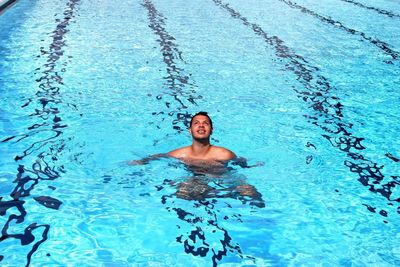 High angle view of shirtless young man swimming in pool