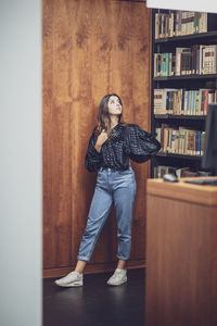 Young woman looking away while standing in library