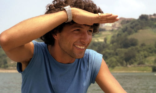 Close-up of smiling young man shielding eyes