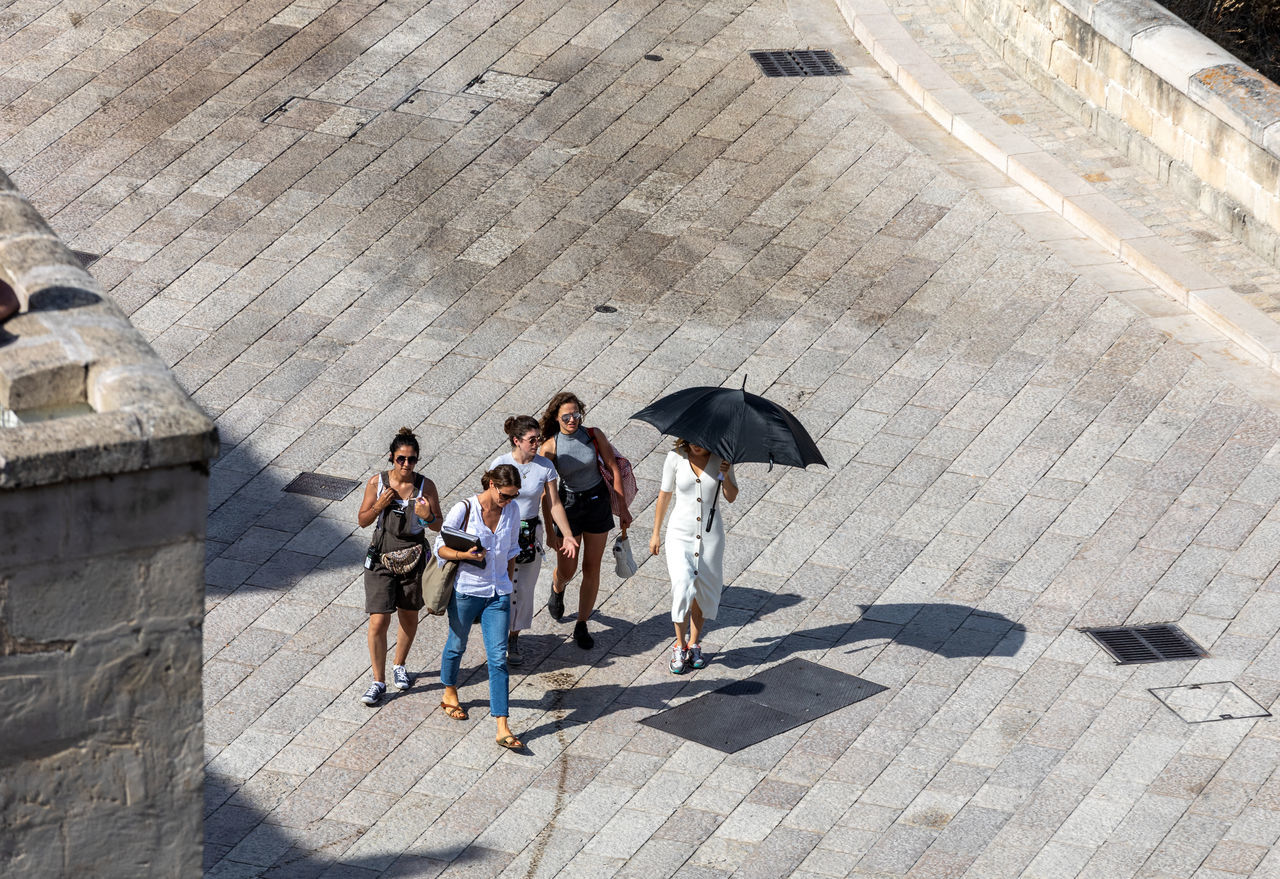 HIGH ANGLE VIEW OF PEOPLE WALKING ON COBBLESTONE STREET