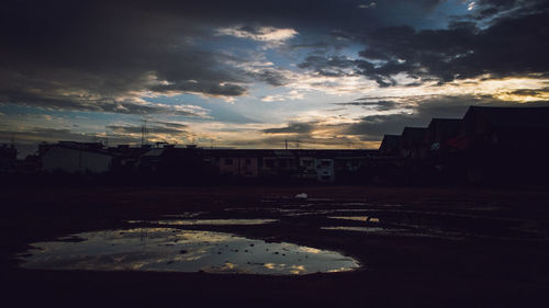 Street by buildings against sky during sunset