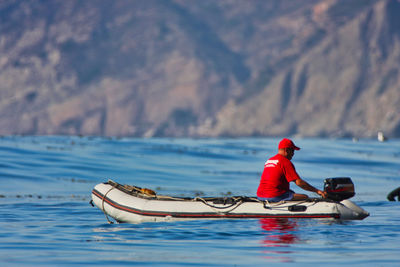 Man in boat on sea against mountain