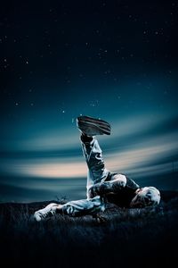 Young man lying down against sky at night