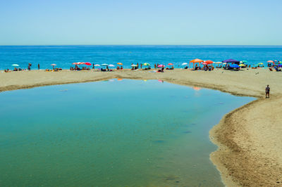 Group of people on beach against clear sky